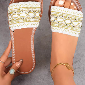 White embroidered artisan open-toe sandals with gold detailing and brown soles.
