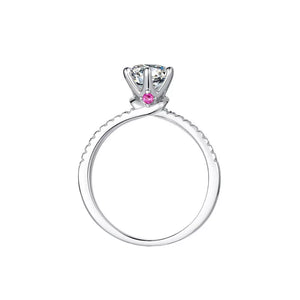 Sterling silver ring with a round moissanite and small pink accent stones on the band.