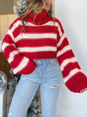 Crimson stripe cropped knit sweater with balloon sleeves and a cowl neck, styled with light wash jeans.