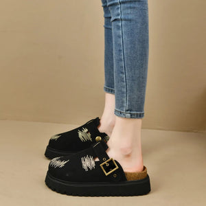 Black embroidered denim platform clogs with buckle detail and cork sole.