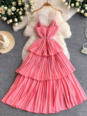 Pink belted midi dress with spaghetti straps, smocked bodice, and tiered pleated skirt.