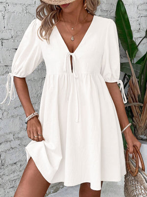 White tie front puff sleeve mini dress with adjustable tie cuffs and a v-neckline.