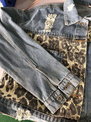 Distressed denim trucker jacket with leopard print panels and button cuffs.