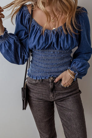 Medium wash denim corset bodice blouson top with smocked waist and cuffs.