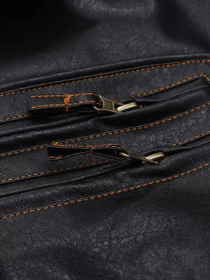 Black faux leather motorcycle coat detail with brass zippers and orange stitching.