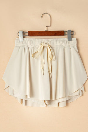 Beige ruffled skort with tie waist detail and elastic waistband.