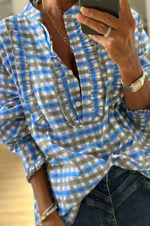 Blue plaid button-down blouse with frilled detail and buttoned neckline.