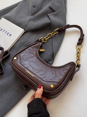 Coffee color crescent shoulder bag with chunky chain accent and textured finish.