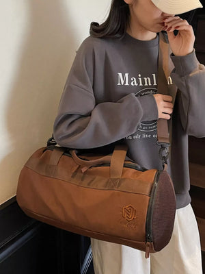 Brown Oxford cloth duffel bag with carry handles and adjustable strap, featuring mesh end caps.