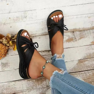 Black leather lace-up cutout slides with bow detail and peep toe.