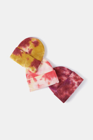 Ribbed knit beanies in tie-dye patterns of mustard/red, pink/yellow, and burgundy.