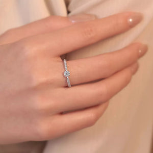 Elegant moissanite ring in sterling silver with a brilliant center stone and pave band.