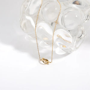 Gold knot pendant necklace with delicate chain, 18K gold-plated.