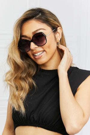 Oversized round black sunglasses with gradient lenses and gold accents.