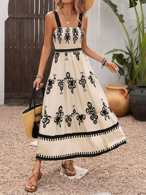 Bohemian smocked maxi dress in cream with black floral print, tiered skirt, and black straps.