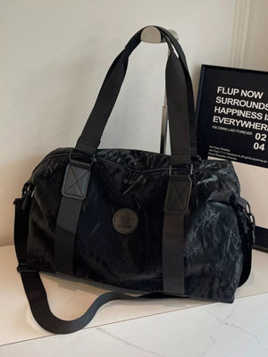 Black medium oxford cloth travel bag with adjustable strap and round logo detail.