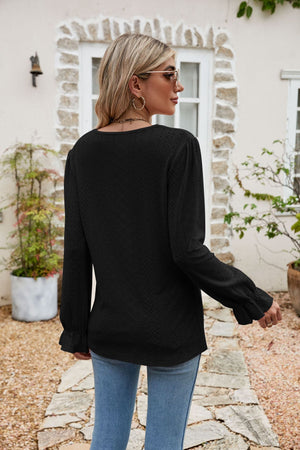 Black eyelet lace blouse with ruffle sleeves and a textured pattern.