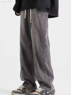 Men's dark gray distressed oversized fit jeans with drawstring waist and wide leg.