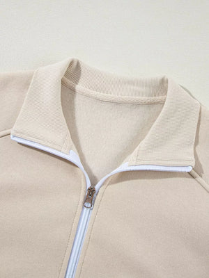 Beige cotton zip-up jacket with ribbed collar and white zipper detail.