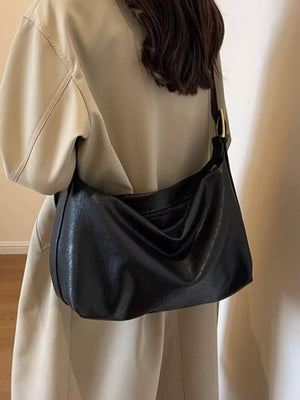 Black leather shoulder bag with adjustable strap and gold buckle detail