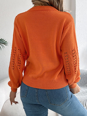 Orange knit sweater with openwork cable knit sleeves and crew neck.
