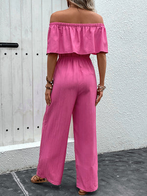 Hot pink off-the-shoulder ruffled waist jumpsuit with wide legs.