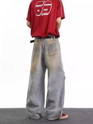 Men's distressed wide leg jeans in blue denim with artful fading and a ripped detail.