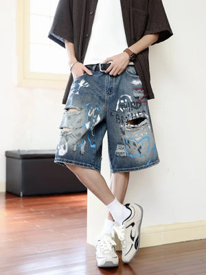 Men's distressed blue denim shorts with graffiti print and rips.