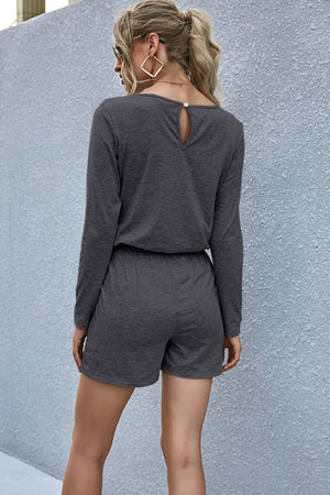 Dark gray jersey romper with long sleeves, elastic waist, and keyhole back detail.