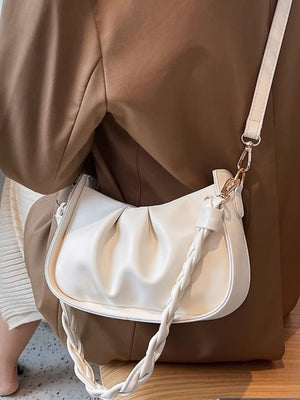 White ruched crossbody bag with braided strap detail and gold hardware.