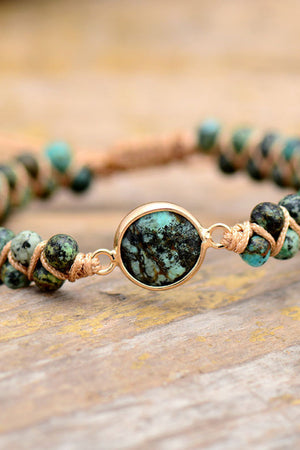 Turquoise beaded bracelet with braided cord and gold-tone center stone detail.