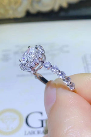 White oval moissanite halo ring with diamond band detail.
