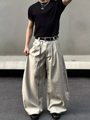 Men's wide leg pants in apricot with pleats and a chain detail belt.