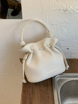 White pu leather cinch-top crossbody bag with knotted handle detail