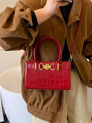 Red crocodile-textured crossbody bag with gold hardware and top handles.