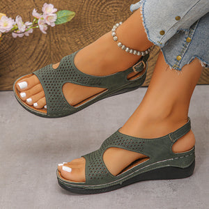 Green cutout wedge sandals with adjustable ankle strap and perforated detail.