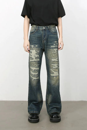 Distressed flare jeans in medium wash denim with graffiti print and ripped details.