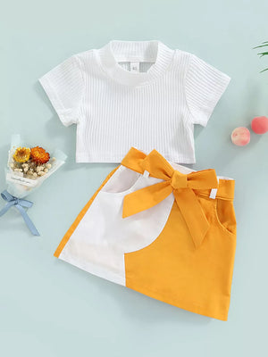 Baby knit top and skirt set with bow detail, white ribbed crop top and yellow colorblock skirt.