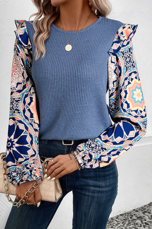 Dusty blue knit top with ruffled printed sleeves and a round neckline.