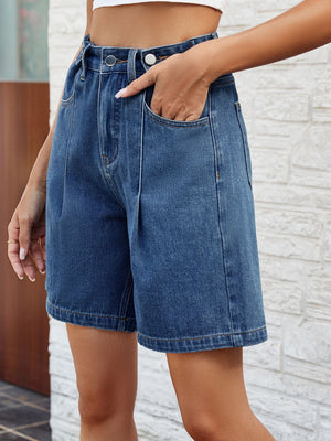 Pleated denim bermuda shorts in medium wash with button closure and front pockets.