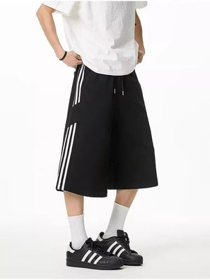 Black cropped sweatpants with white side stripes and drawstring waist.