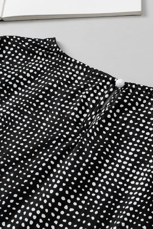 Black dotted blouse with puff sleeves and pearl button detail at the neckline.
