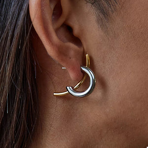 Intertwined two-tone c-hoop earrings in silver and gold metal with a contemporary design.