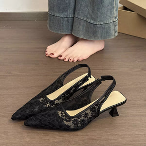 Black lace slingback kitten heels with floral pattern and pointed toe.