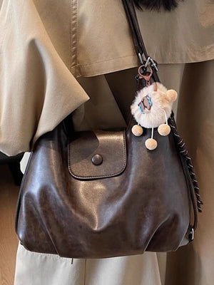 Vintage pu leather shoulder bag in olive brown with a distressed finish and playful charm.