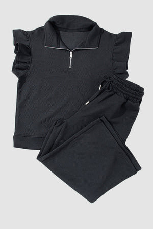 Black textured loungewear set with zip-up top and ruffle sleeves, and drawstring pants.
