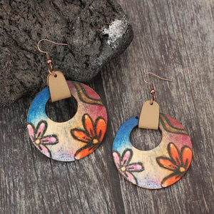 Painted floral wood hoop earrings with leather accents and copper hooks.