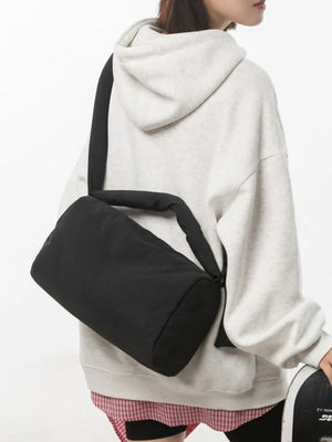 Black padded knot shoulder bag with adjustable strap, worn casually.