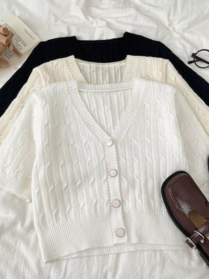 White cable-knit cropped cardigan with button front and short sleeves.