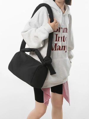 Black padded knot shoulder bag with a cylindrical shape and knotted strap detail.